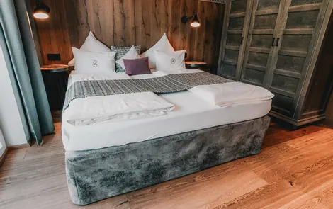 Der Pinzgauer Gemütliches Hotelzimmer mit Doppelbett, Holzverkleidung und Kleiderschrank